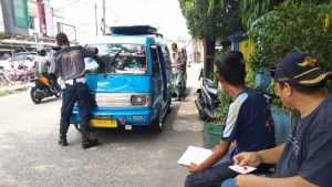 Petanas Dishub menempelkan stiker trayek angkot biru di pinggir jalan Bama Pandeglang Banten