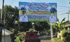 Baliho resmi proyek Sedang Ada Bang Andra terpasang di atas jalan desa Pandeglang