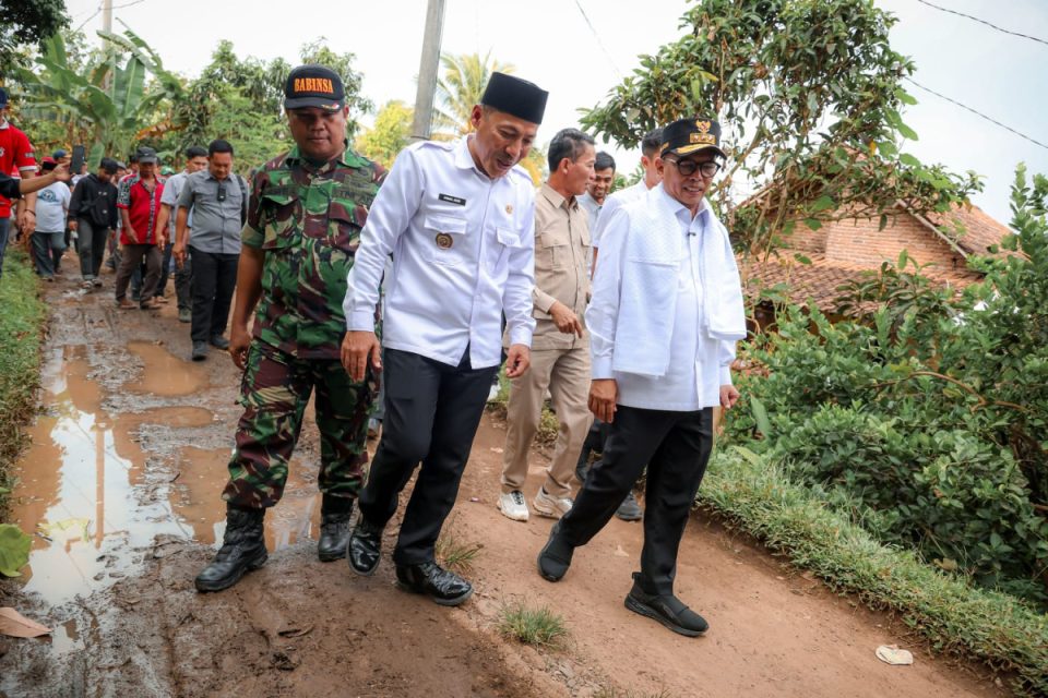 Pejabat pemerintah meninjau jalan desa yang rusak parah dan berlumpur