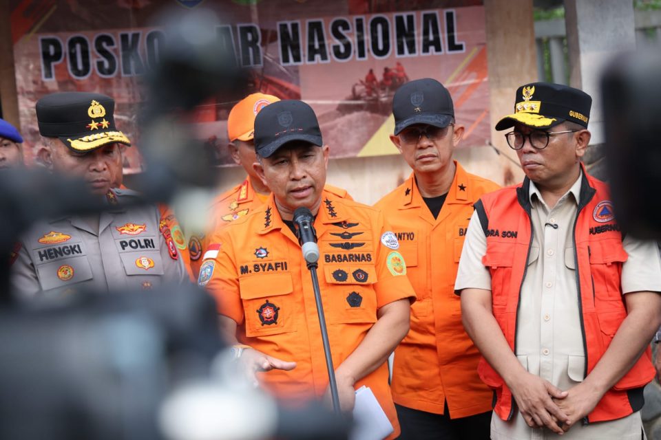 Gubernur Banten Andra Soni menggunakan rompi jingga bertuliskan namanya sedang mendampingi petugas Basarnas berbaju oranye yang berbicara di depan mikrofon saat konferensi pers di Posko SAR Nasional.